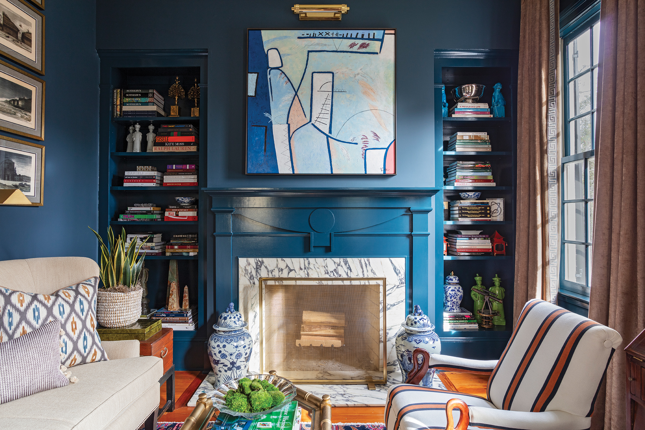 Abstract art, and bold paint colors, like Farrow &amp; Ball “Hague Blue” in the living room, are juxtaposed with antique furnishings.“Brown furniture is very stuffy in general so you have to balance it,” says John.