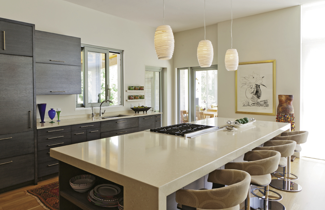 The addition encompasses an open living, dining, and kitchen space, which fosters a loft-like feel. A neutral color palette ensures the interior design complements the stunning views and prized artworks, like the black-and-white Andy Warhol in the kitchen.