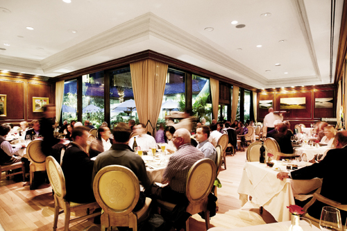 The decor strikes a classic tone with wood-paneled walls, elegant drapery, and white tablecloths.