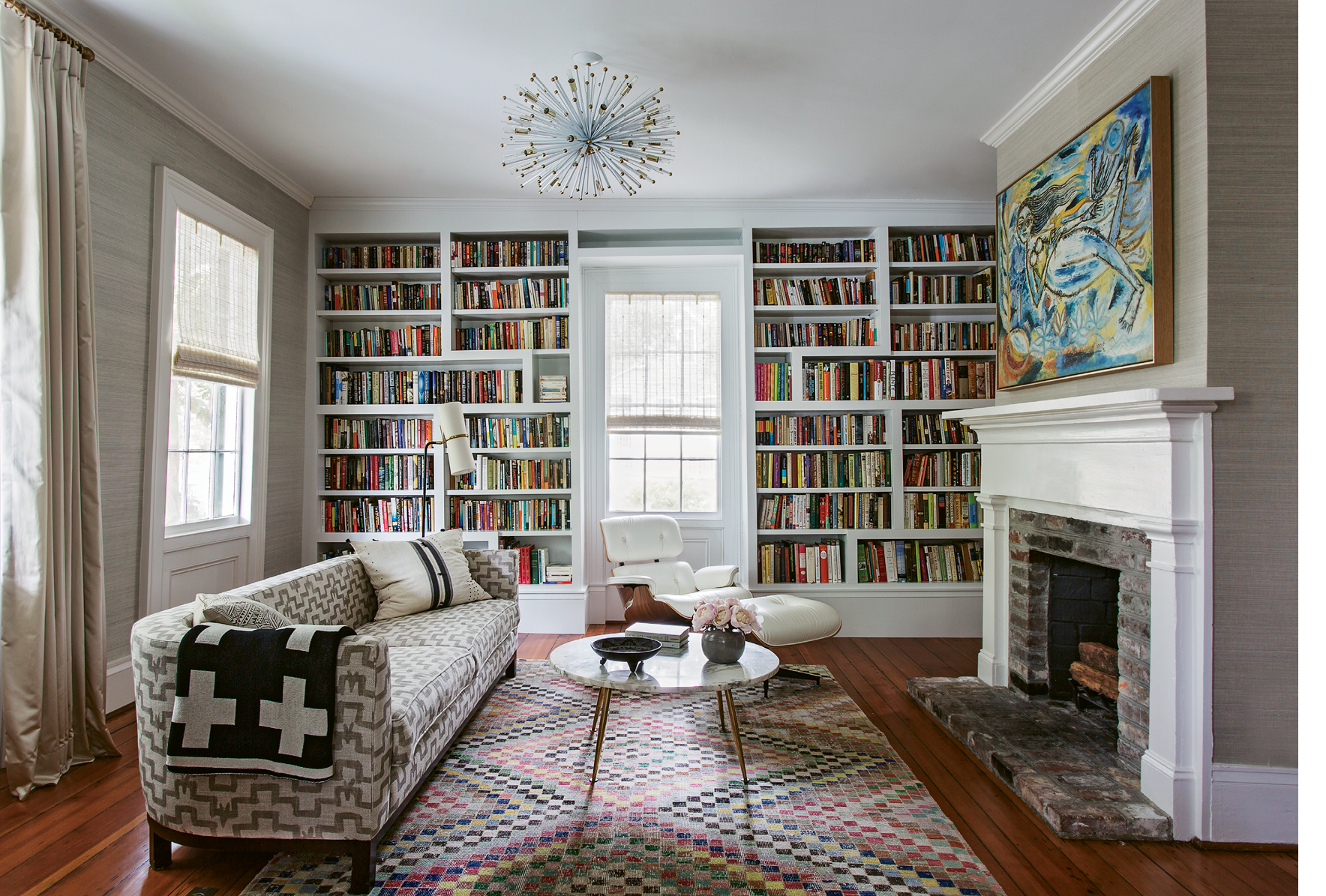 PATTERN PLAY: In the library, a splashy yellow-and-blue painting by Indian artist Laxman Pai lives in harmony with a graphic pink rug and a patterned vintage sofa. Keenan says mixing textiles helps a home feel “more lived-in and not so perfect.”