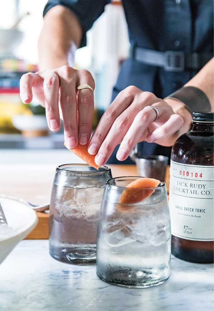Erin mixes cocktails with 11/2 ounce Ethereal Gin, 1/2 ounce Jack Rudy Tonic Syrup, ice, grapefruit La Croix, and a grapefruit peel garnish.
