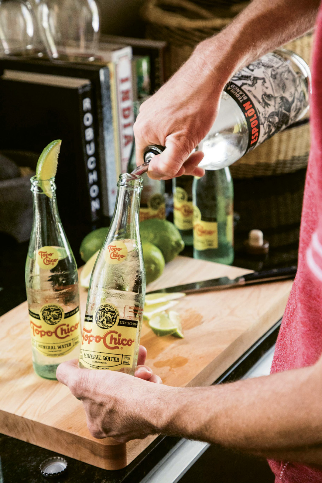 Lewis mixes cocktails with equal parts Topo Chico and silver tequila, garnished with lime.