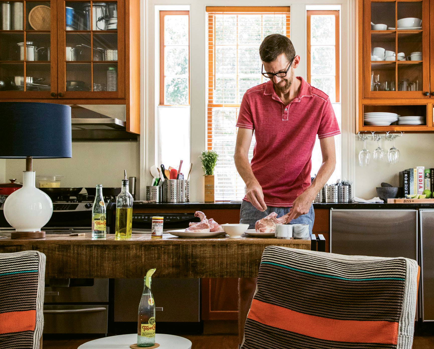 Inside his Southwest-meets-modern Elliotborough home, John Lewis seasons center-cut pork chops while sipping on a Topo Chico cocktail.