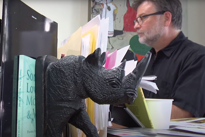 Sloan at work in his office, where a faux boulder hangs on a rusty chain over his head. “It helps me concentrate,” he says.