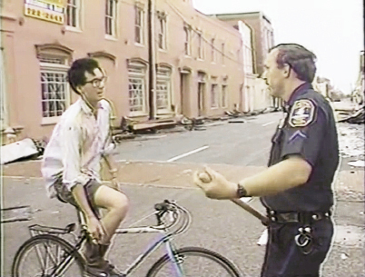 Downtown, a bakery owner, attempting to check on his business, was given an update by one of the policemen stationed to prevent looting.