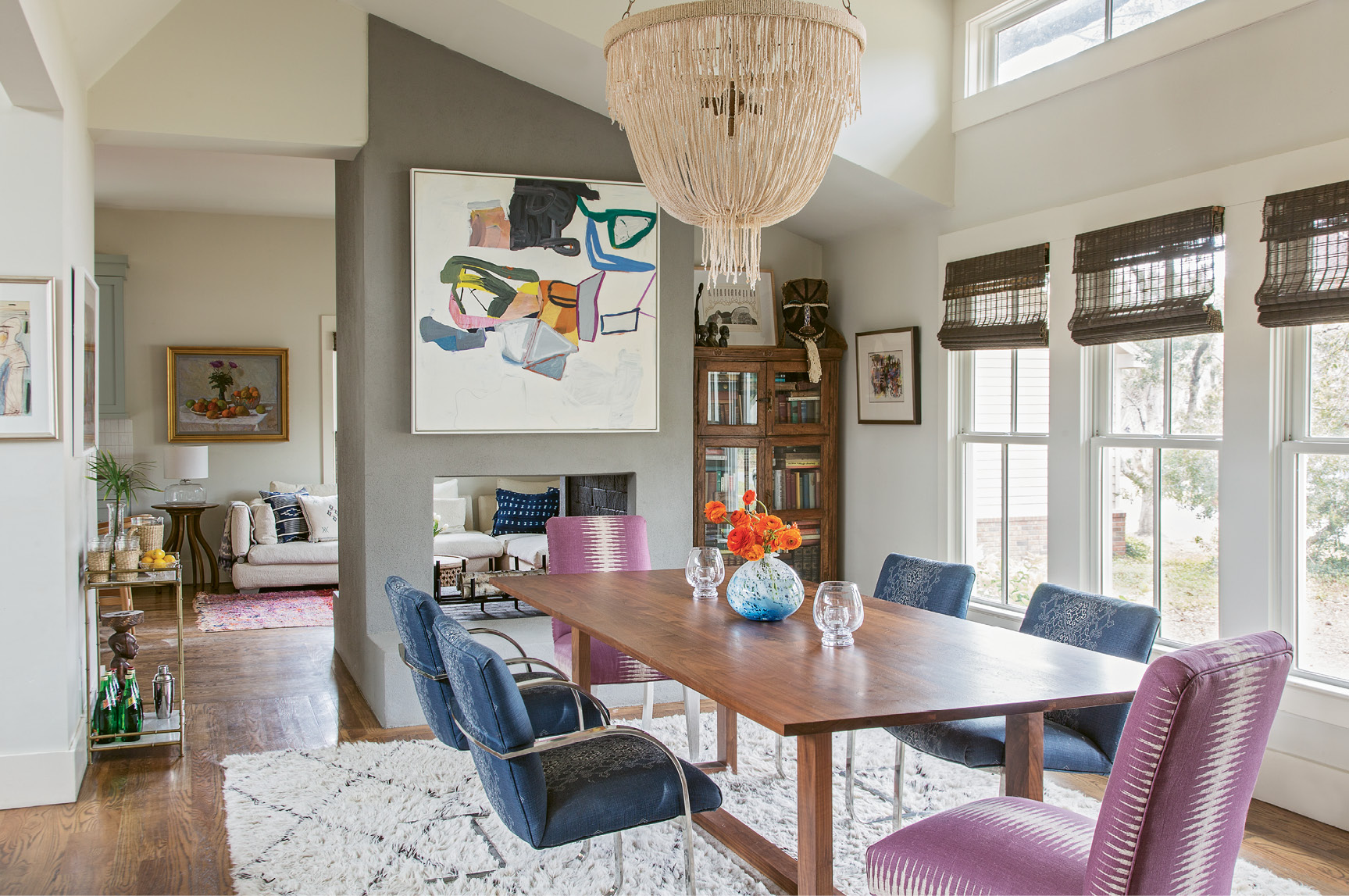 ...the slipper chairs on either end of the dining table were handed down from a friend and recovered in a fresh fabric, and the rest of the dining chairs were scored on eBay. An abstract painting by Brian Coleman adds a dash of color and texture above the wraparound fireplace, which was stuccoed during the renovation for a more modern, streamlined look.