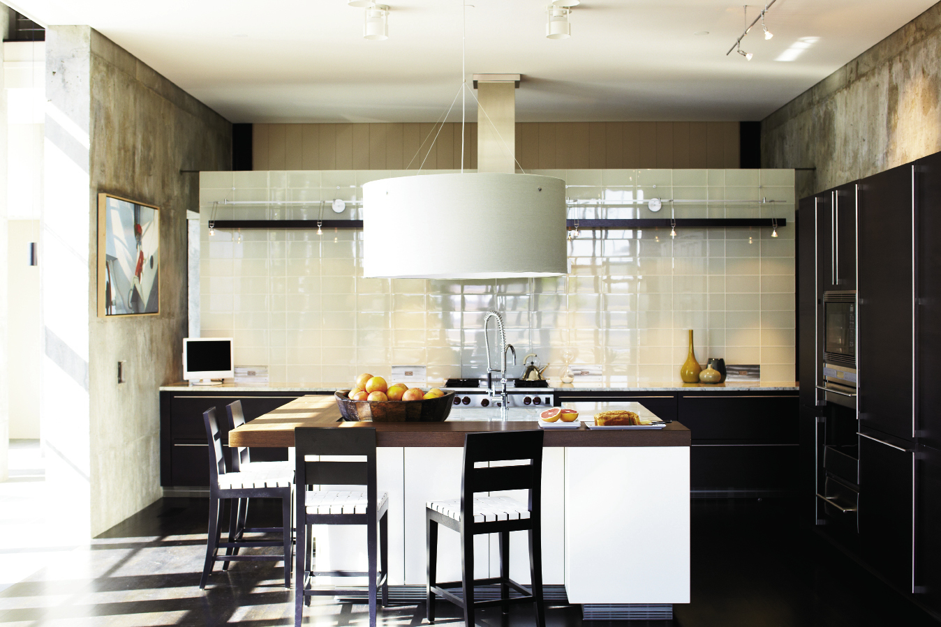 Island Living: The Siematic-designed kitchen features wenge cabinetry and woodwork and a large round shade pendant; a floating wall of light green glass subway tiles offers a cool and contemporary backdrop.