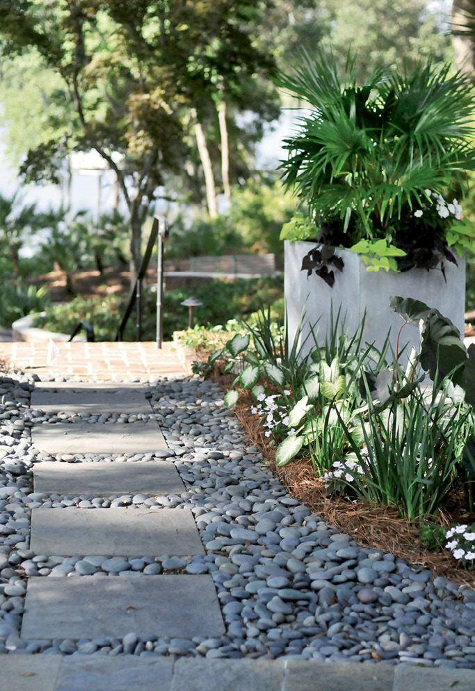A Stone’s Throw: Mexican river rocks add texture and function (covering spots where sod suffered from too much shade) along a path toward the river and boathouse.