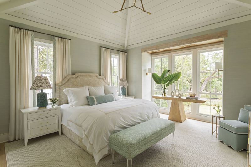 Rest &amp; Relaxation: The primary suite was designed as a counterpoint to the couple’s active lifestyle—they stay busy with golf, fly-fishing, and other outdoor pursuits. Elebash sourced plush upholstery, including a custom headboard wrapped in Ann McGuire Studio fabric and a scalloped slipper chair by Oomph. A floor-to-ceiling window alcove brings the outdoors in.