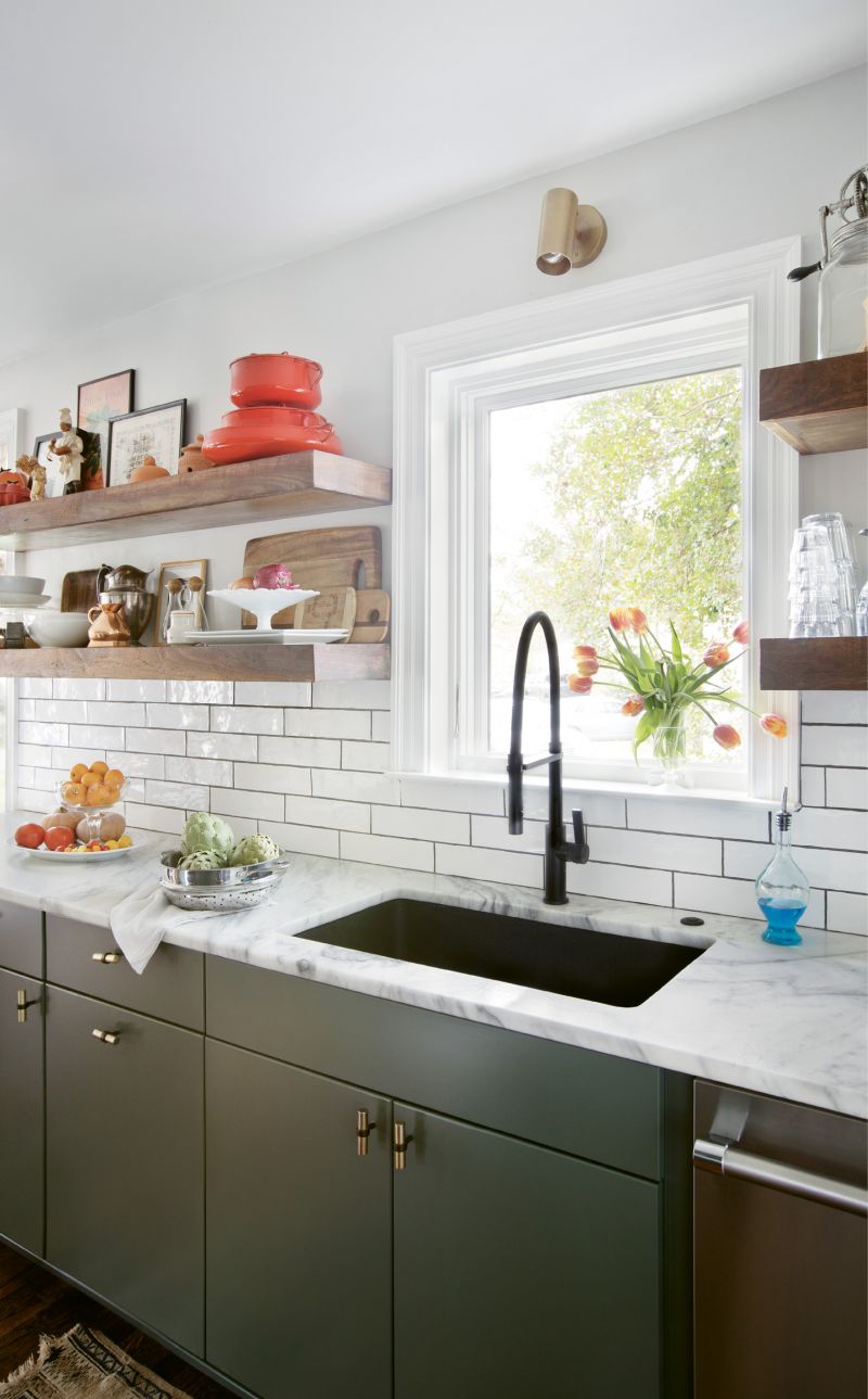 WHERE THE MAGIC HAPPENS: Thanks to the removal of a wall between the kitchen and living room, cooking for guests is no longer claustrophobic. The refreshed space makes good use of local materials, including the faucet from Molufs and painted concrete backsplash from Palmetto Tile. “Tile can really make a space without being too distracting,” Carrie notes. Quartzite countertops, flat-face cabinets, and hardware from Anthropologie add to the clean look, while a rotating display of objects provides the finishing touch. “We love the open shelves, and I find I’m always rearranging and shuffling things around; it is really inspiring to see fresh produce and artwork in the kitchen,” she continues.