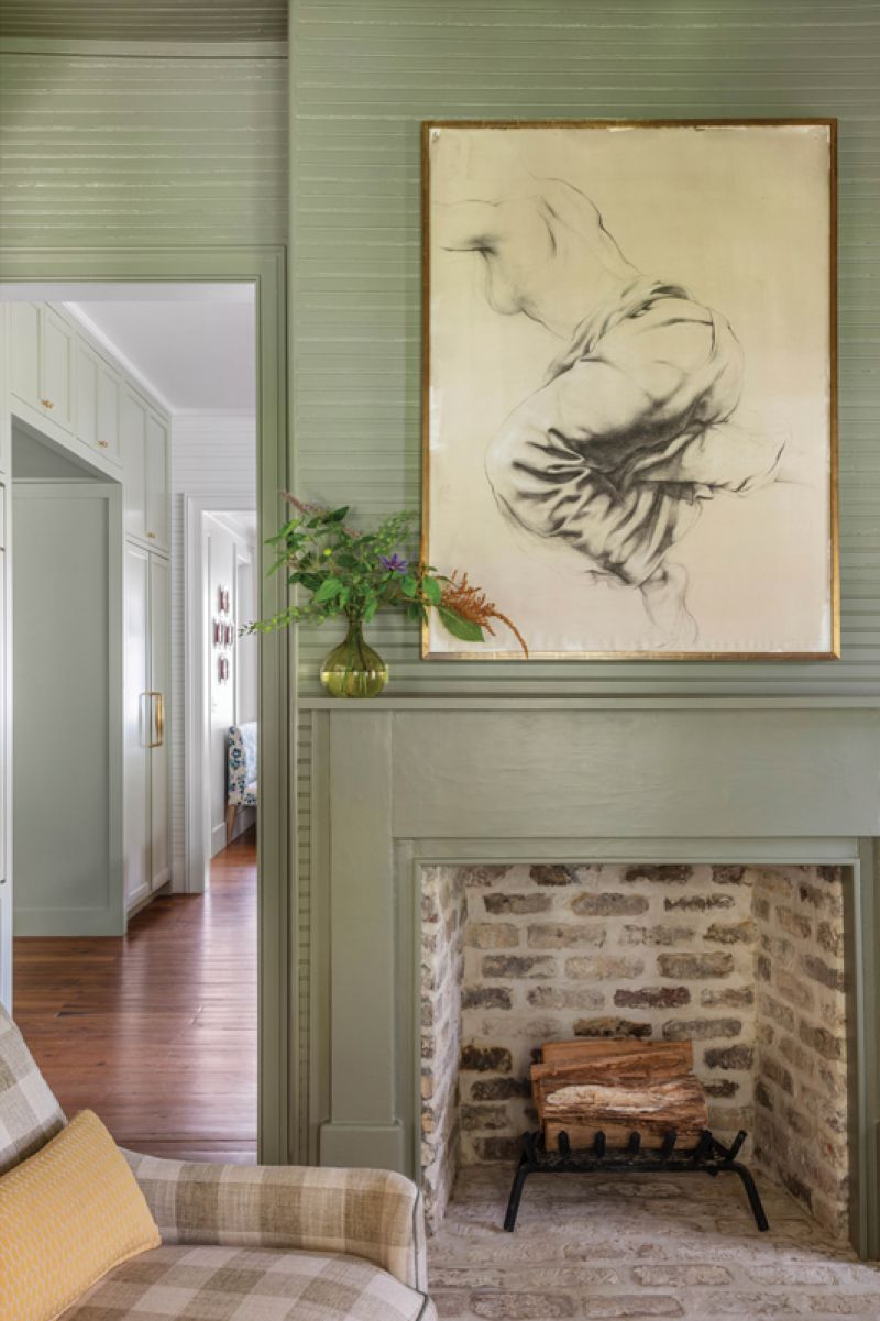 A contemporary “Mantis” chandelier from Anthropologie and a French provincial antique chest pair with a charcoal study by Jill Hooper over the original fireplace to merge modern and traditional