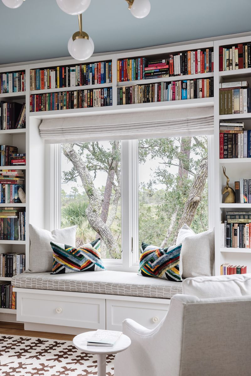 A window seat situated in the built-in bookshelves.