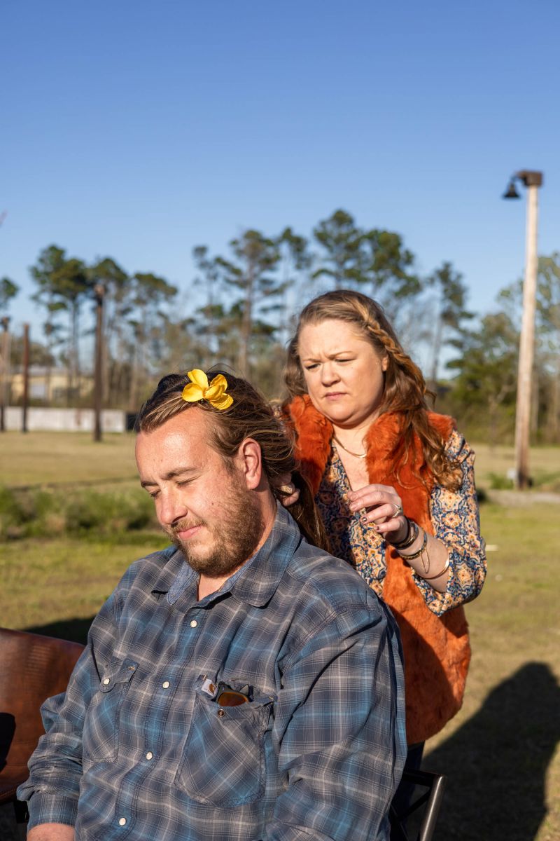 A staff member of Lava Salon adds flowers to the hair of attendee Finnegan Culotta.