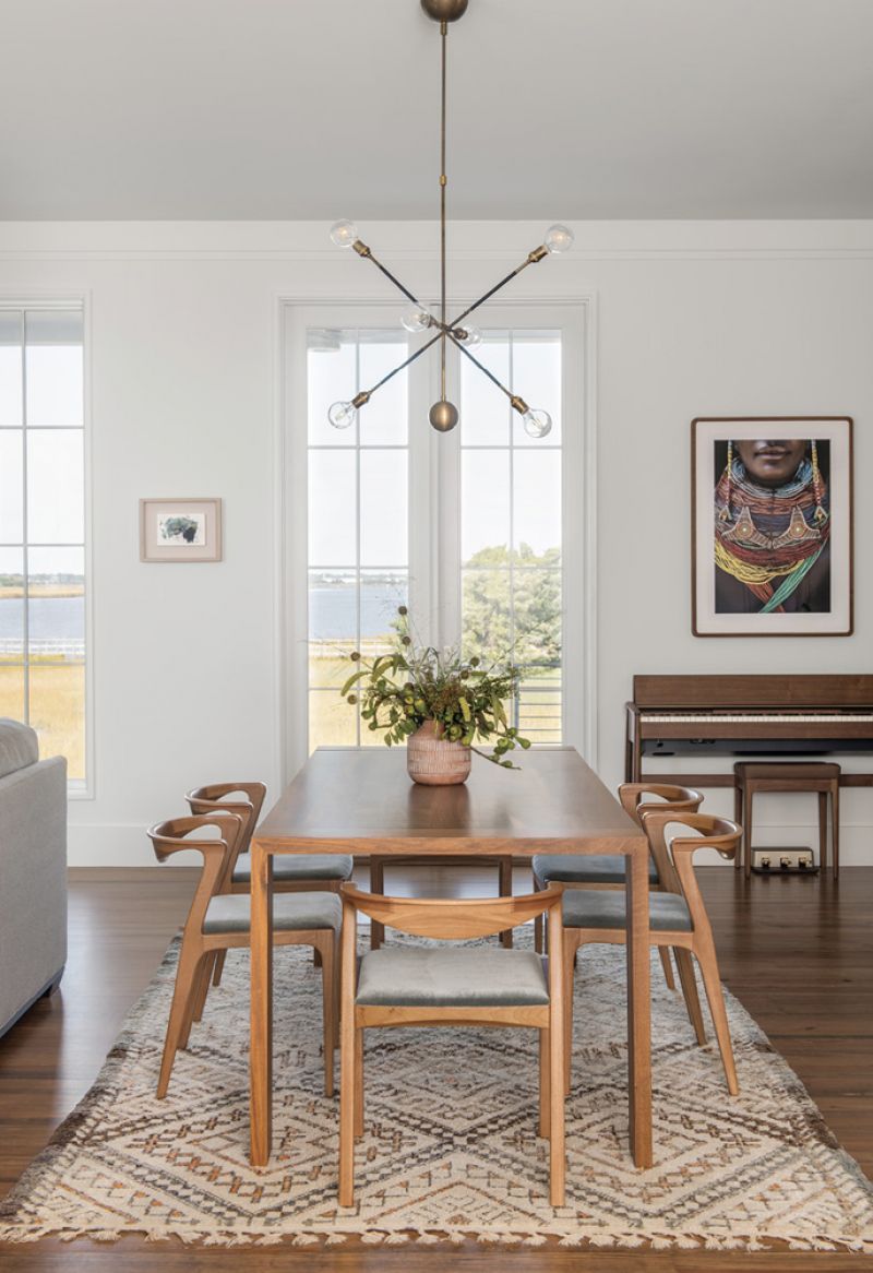 Dining in Style: Separating the kitchen from the living room, the dining area features a Ligne Roset “Eaton” table surrounded by Brazilian wood “Duda” chairs from Sossego Design. A vintage Moroccan rug from Elegant Nomad covers the old-growth pine floors that connect the spaces. The scene is illuminated by a “Highwire” fixture from the New York-based Apparatus Studio.